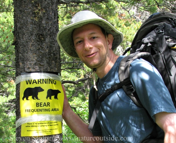 hiker beside bear warning sign Glacier National Park