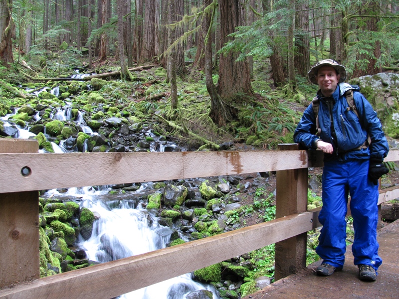 hiker by waterfall in rain in olympic national park