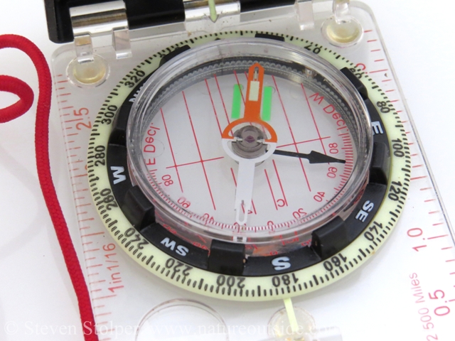 Red Fred in the shed. My fancy compass has green bars instead of a "shed." My shed has been adjusted for local declination. The small arrow at the top of the bezel, pointing at the white line, shows geographic north.