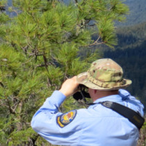 hiker on mountain looking through binoculars