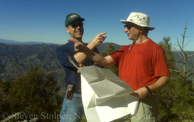 two hikers with map pointing in opposite directions