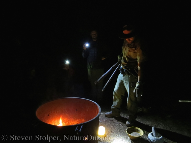 Ranger seizes a rock from the fire using wood branches as tongs