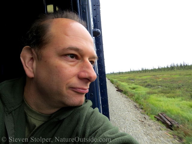 person looking out of train between cars