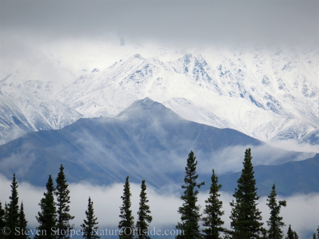 The snow covered peaks disappear into the threatening clouds